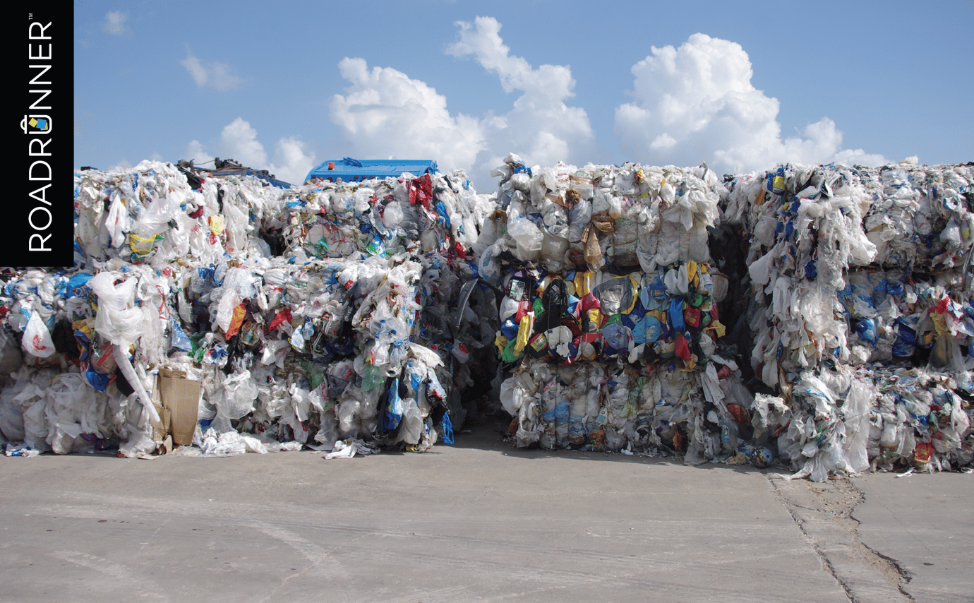 Stacks of sorted and baled plastics from a materials recovery facility under blue sky.