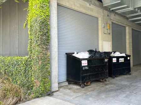 2 dumpsters sit outside of a building