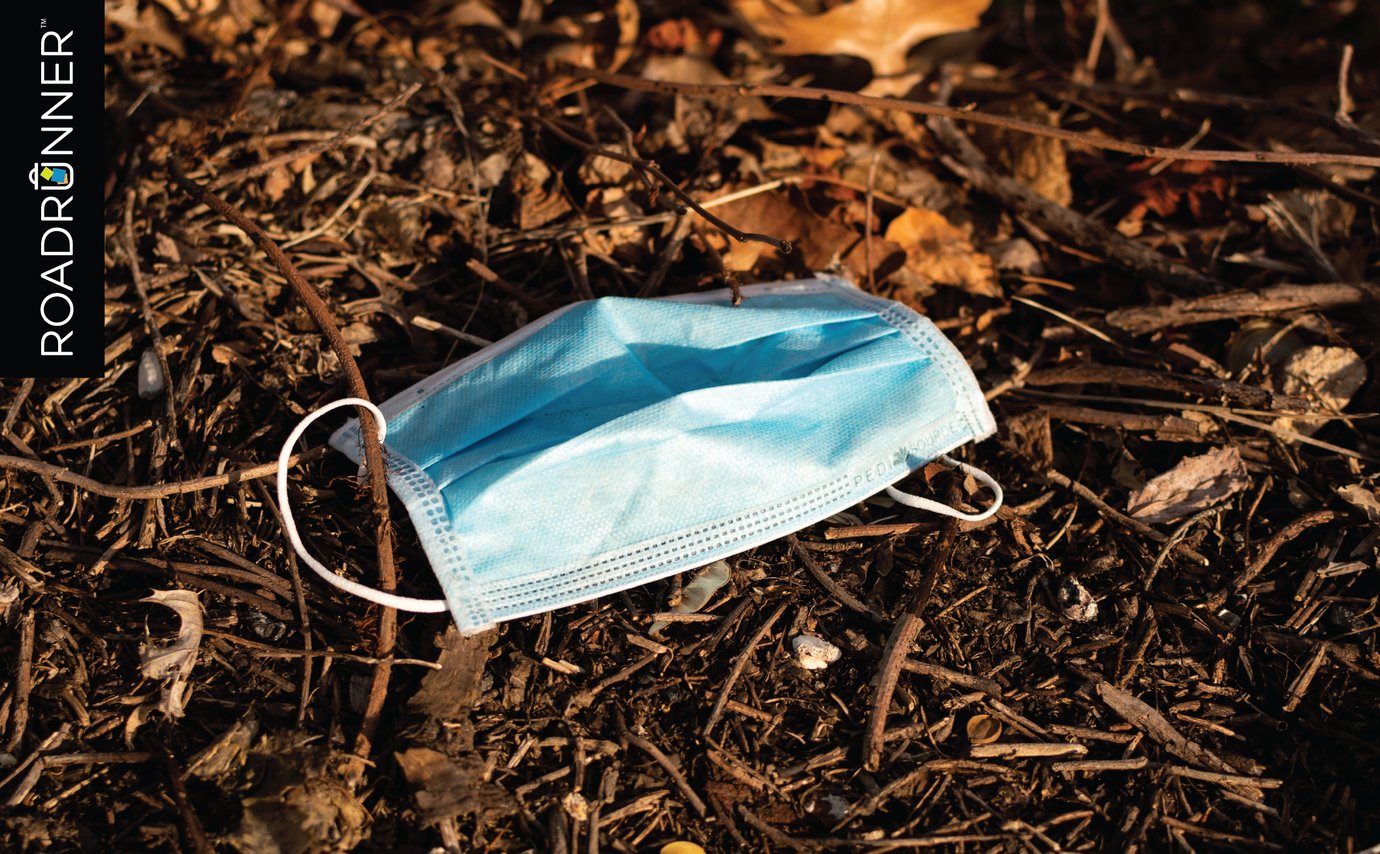 Blue face mask littered on pine needles and leaves.