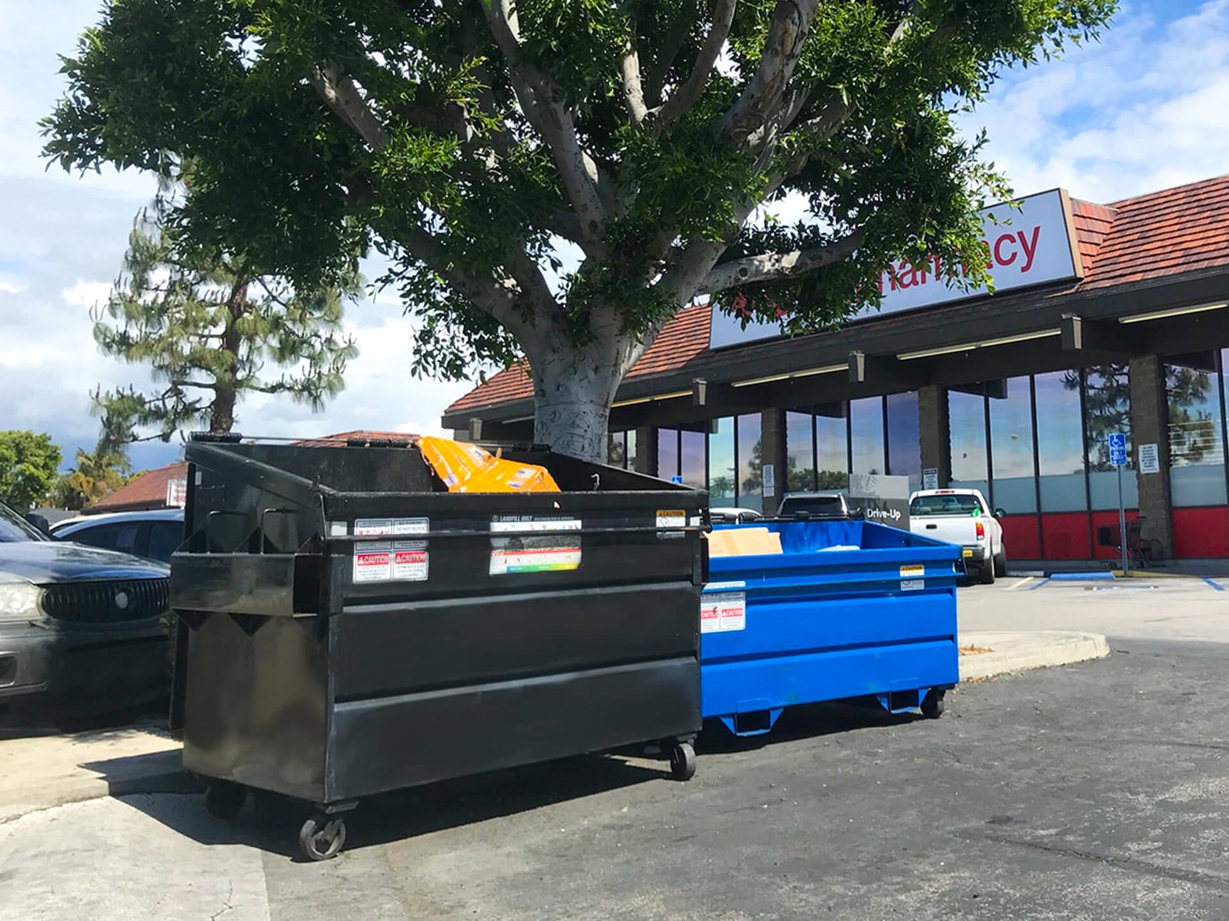 two dumpsters in front of a convenience store