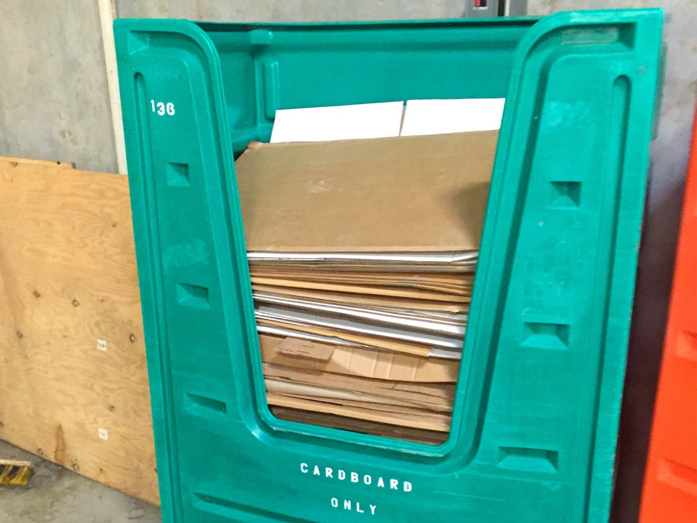 Green recycling crate full of stacked cardboard