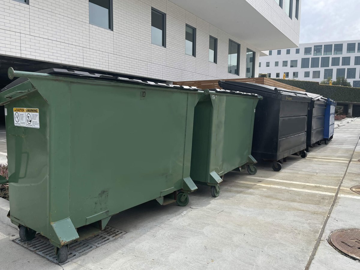 multiple dumpsters outside of a building