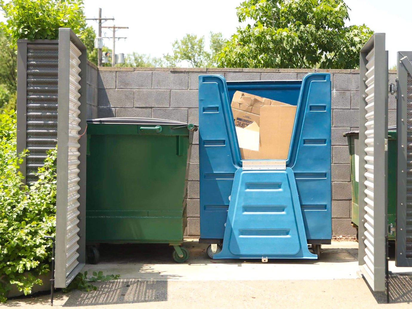 Dumpsters and recycling crates in a corral