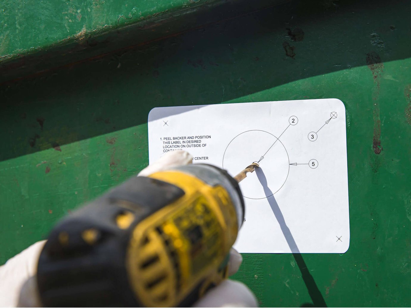 A technician drilling into a dumpster