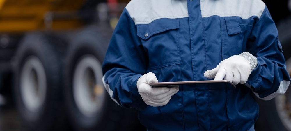 A worker uses a tablet for waste management.