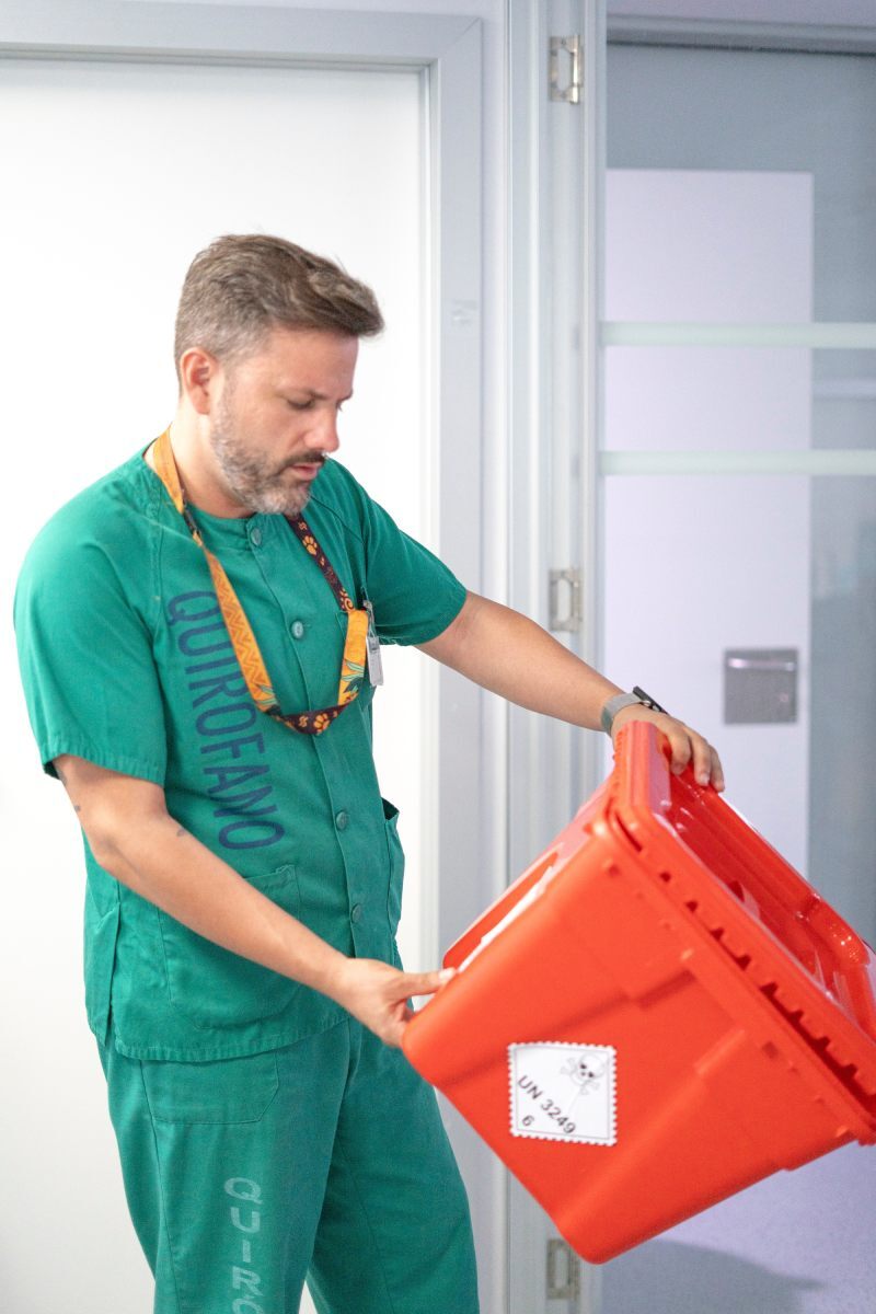 A healthcare worker inspects a biohazard disposal bin