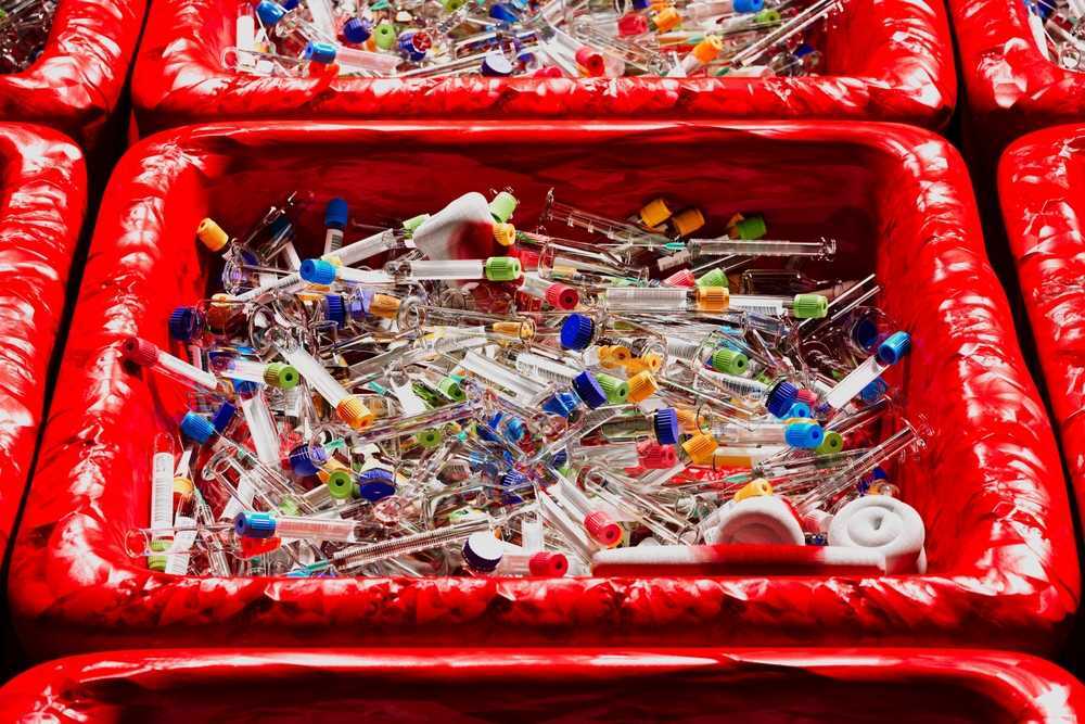 A very full biohazard container overflowing with sharps.