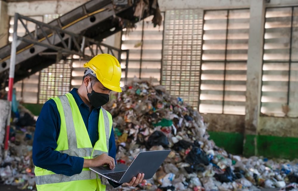 A waste management engineer uses a laptop.